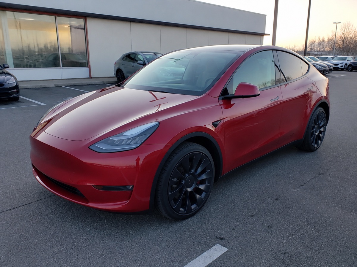 Red electric crossover photographed in a dealership parking lot