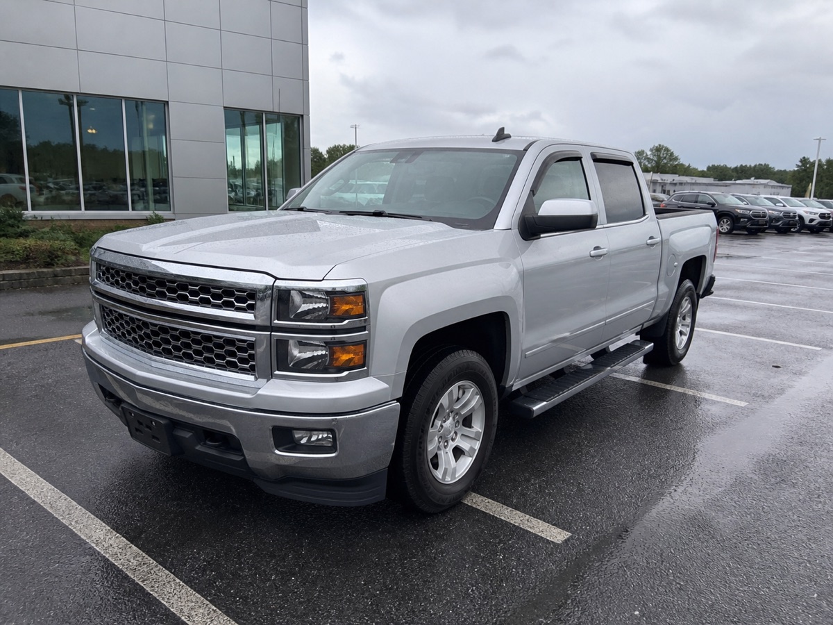 Silver pickup photographed on a wet dealership lot